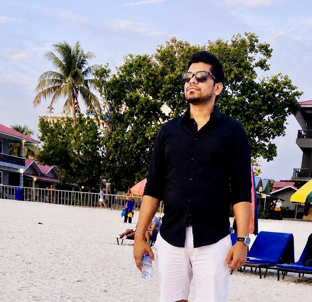 Manas Majhi standing on a white sand beach, looking off to the side