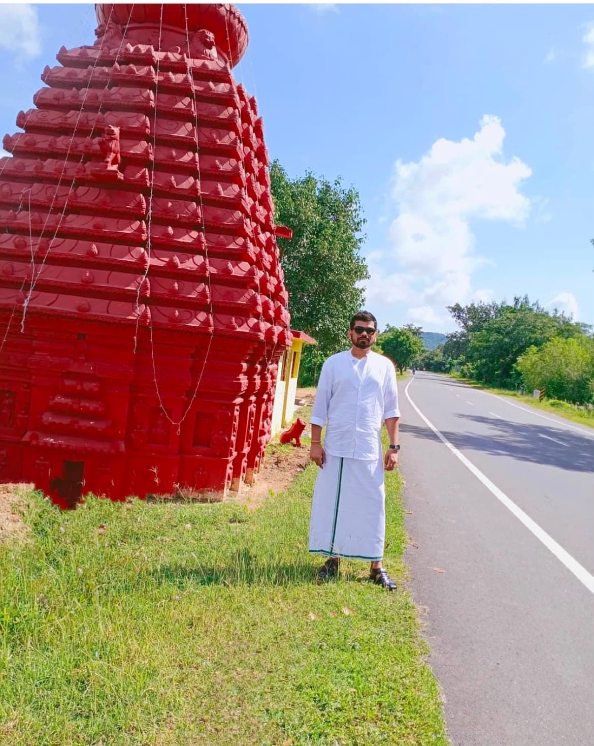 Manas Majhi in white dhoti beside a red temple, Odisha