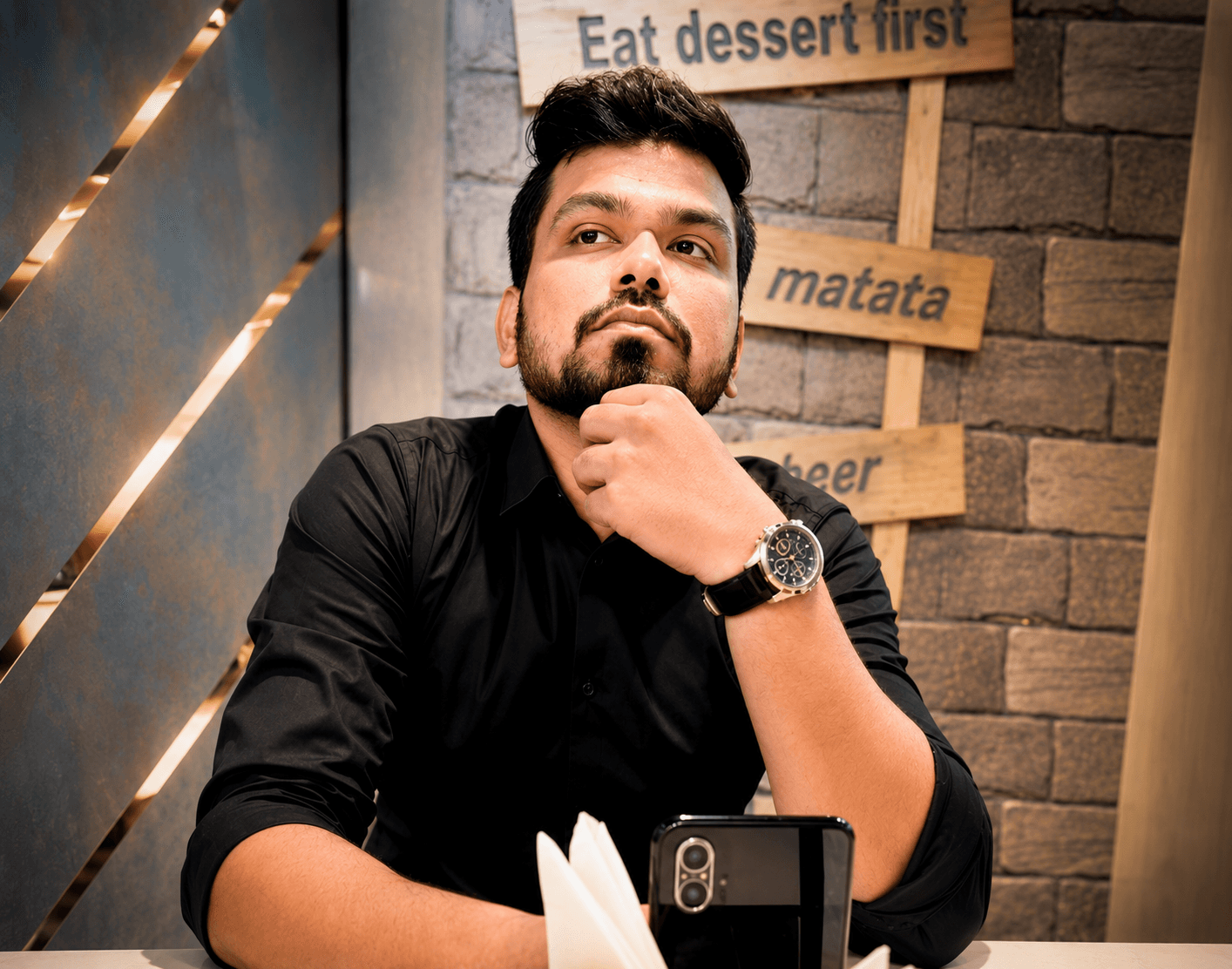 Manas Majhi in a black shirt at a restaurant, thoughtful pose