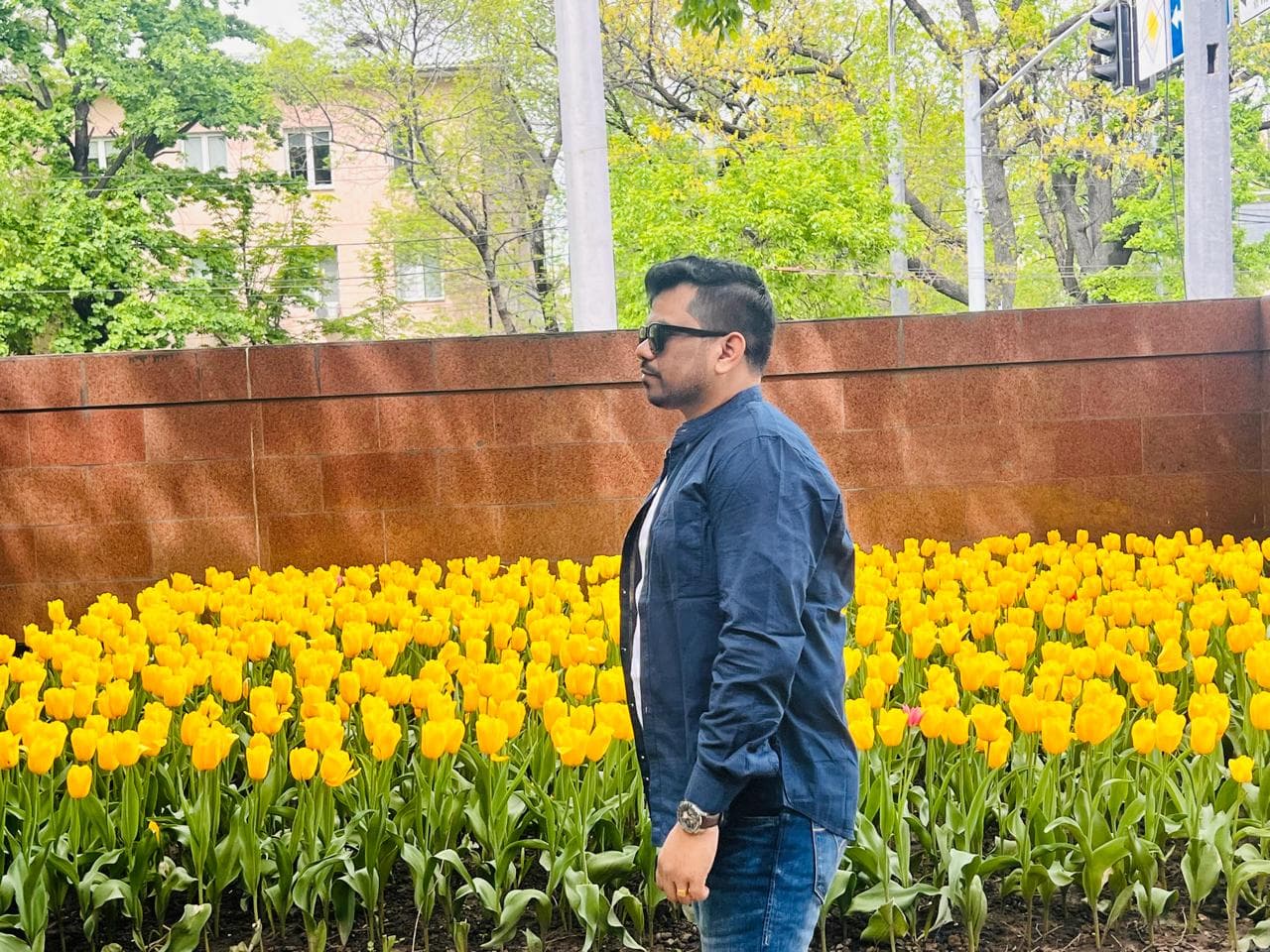 Manas Majhi standing in front of a field of yellow tulips