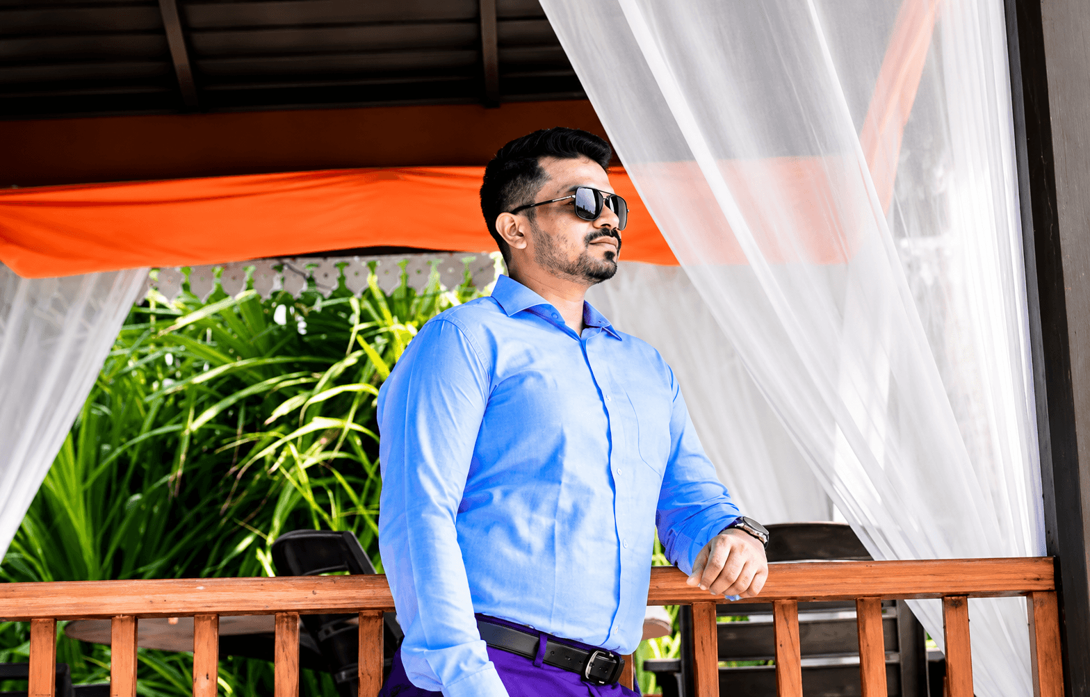Manas Majhi standing on a resort balcony in a blue shirt